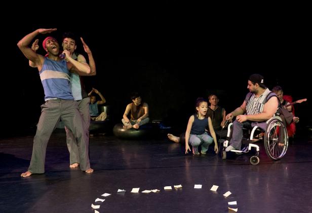 Eine Gruppe von Darstellern unterschiedlichen Alters und Fähigkeiten auf einer Bühne.