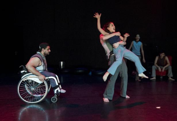 Eine Tanzgruppe führt eine Performance auf, darunter ein Mann im Rollstuhl.