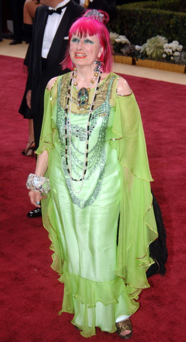 Eine Frau mit pinkfarbenen Haaren und einem grünen Kleid auf einem roten Teppich.