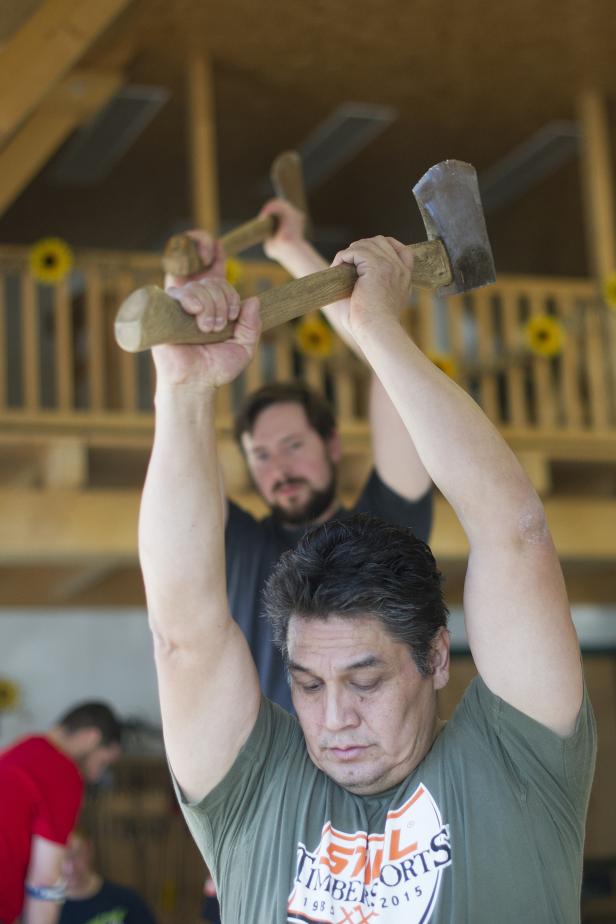 Zwei Männer nehmen an einem Holzhackwettbewerb teil.
