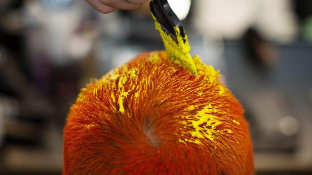 Gelbe Farbe wird mit einem Pinsel auf rotes Haar aufgetragen.