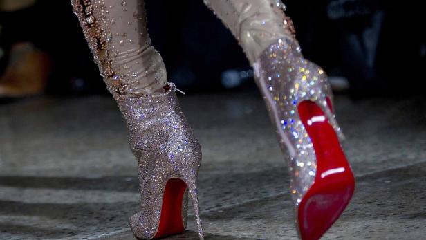 Nahaufnahme von glitzernden High-Heel-Stiefeletten mit roten Sohlen.