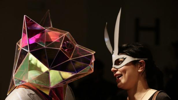 Eine Frau mit Hasenmaske unterhält sich mit einer Person mit einer geometrischen Wolfsmaske.