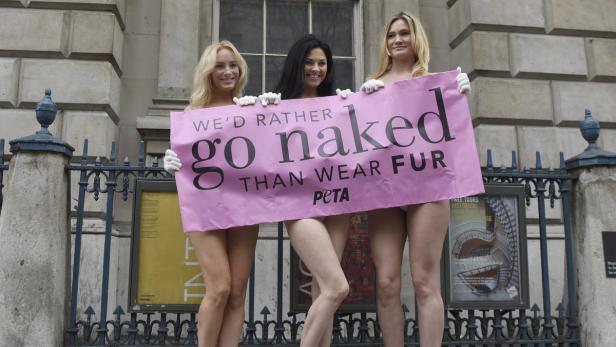 Drei Frauen halten ein rosa PETA-Banner mit der Aufschrift „We'd rather go naked than wear fur“.