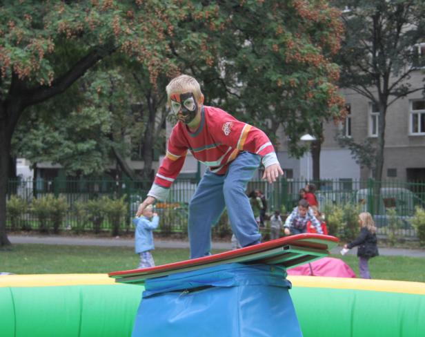Ein Junge mit Gesichtsbemalung balanciert auf einem Surfbrett in einem Park.