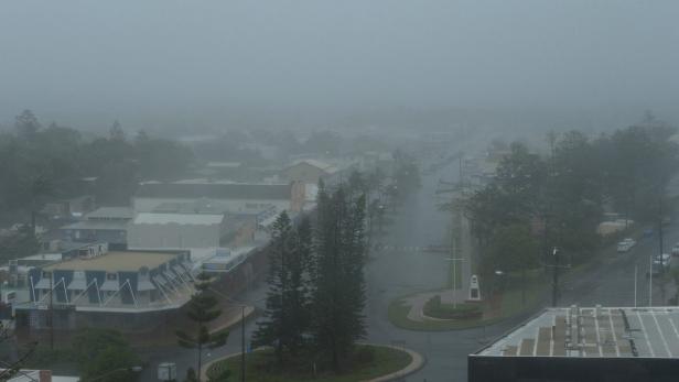 Dichte Nebel hängen über einer Stadt mit Straßen und Gebäuden.