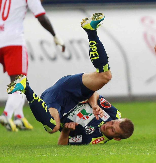 Ein Fußballspieler liegt nach einem Sturz auf dem Rasen.