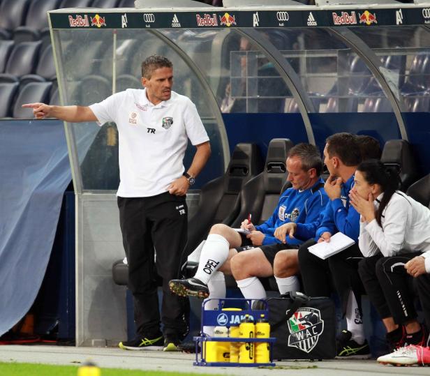 Ein Fußballtrainer gibt Anweisungen, während das Team auf der Bank sitzt.