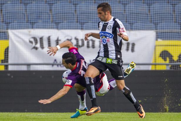 Zwei Fußballspieler kämpfen um den Ball auf dem Spielfeld.