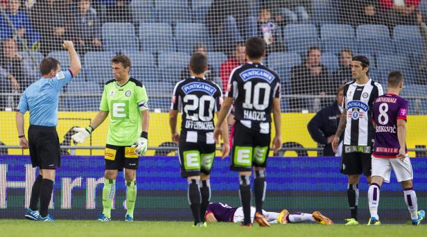 Ein Schiedsrichter zeigt einem Torwart die Rote Karte, während andere Spieler zusehen.