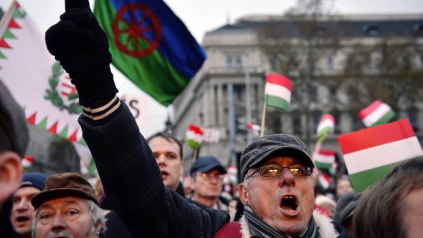 Eine Menschenmenge demonstriert mit ungarischen und Roma-Flaggen.