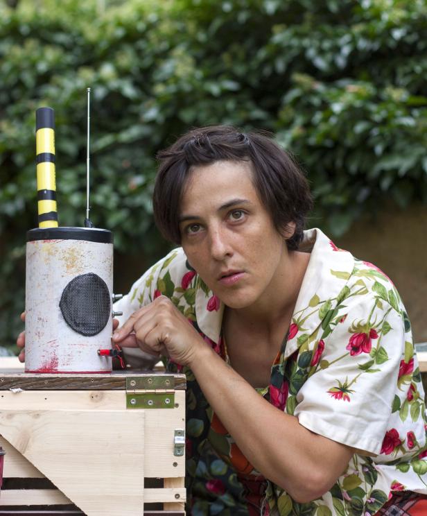 Eine Frau bedient ein selbstgebautes Radio mit Antenne und Lautsprecher.