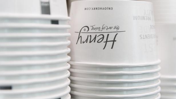 Ein Stapel weißer Pappbecher mit dem Aufdruck „Henry – the art of living“.