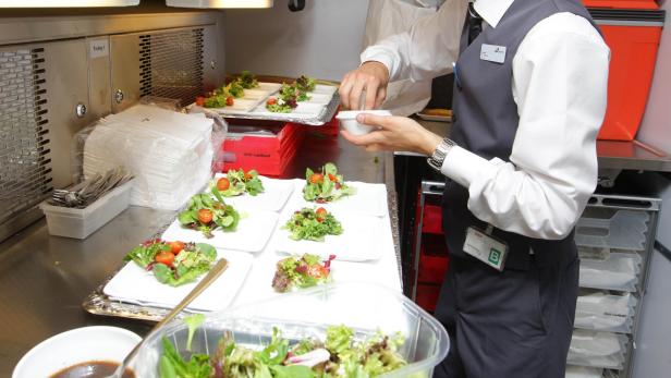 Ein Steward bereitet Salate in einer Bordküche zu.