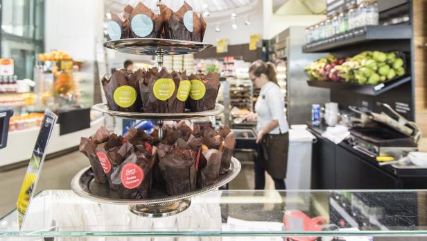 Ein dreistöckiger Servierständer präsentiert verschiedene Schokoladenmuffins in einem Café.