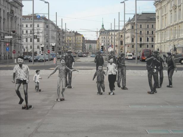 Eine Straßenszene in Wien mit einer Installation von Figurengruppen.