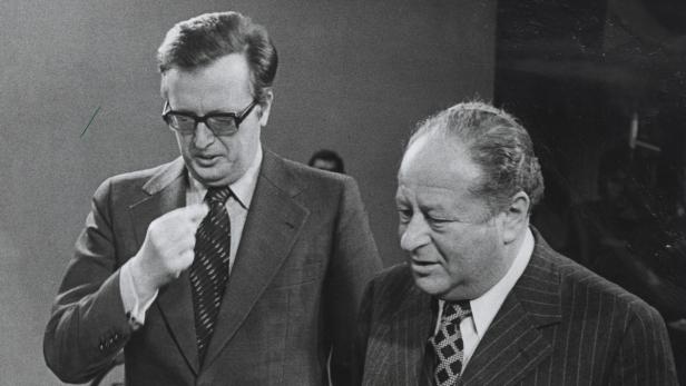 Helmut Schmidt und ein weiterer Mann in Anzügen stehen zusammen.