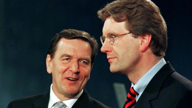 Gerhard Schröder und ein weiterer Mann im Anzug stehen nebeneinander.
