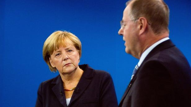 Angela Merkel während einer Diskussion mit einem Mann im Anzug.