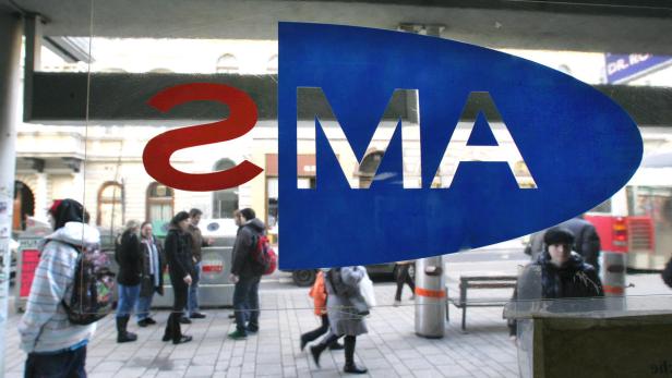 Ein blaues Schild mit der Aufschrift „SMA“ vor einer belebten Straße.