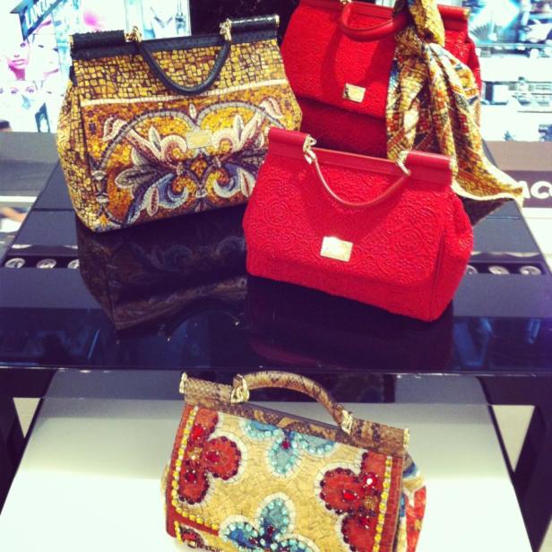 Mehrere Dolce & Gabbana Handtaschen sind auf einem schwarzen Tisch ausgestellt.