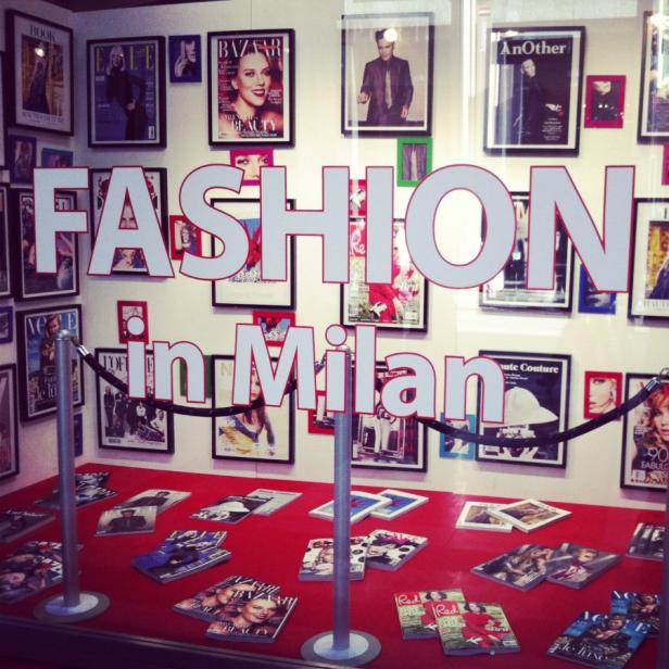Ein Schaufenster mit dem Schriftzug „Fashion in Milan“ und Modezeitschriften.