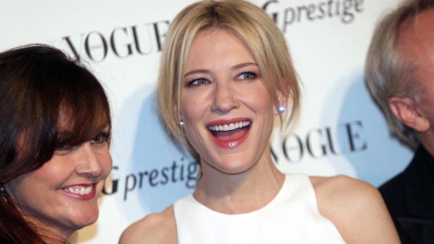 Cate Blanchett lächelt auf einer Veranstaltung neben anderen Personen.