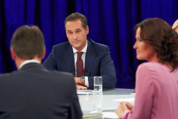 Ein Mann im Anzug sitzt an einem Tisch während einer Diskussion.