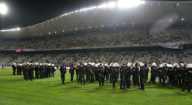 Polizisten stehen auf dem Rasen in einem Fußballstadion vor Zuschauern.