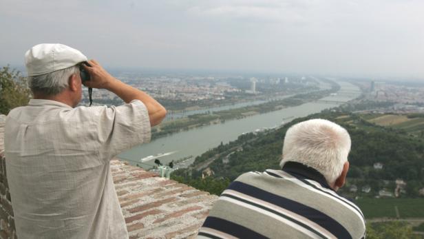 Zwei Männer blicken von einer Anhöhe auf Wien und die Donau.