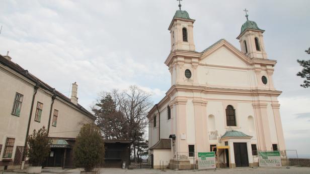 Eine Kirche mit zwei Türmen und einem angrenzenden Gebäude unter bewölktem Himmel.