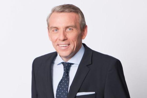 Ein Mann im Anzug lächelt in die Kamera.