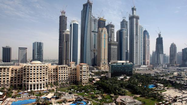 Blick auf die Skyline von Dubai mit zahlreichen Wolkenkratzern und einem Hotelresort im Vordergrund.