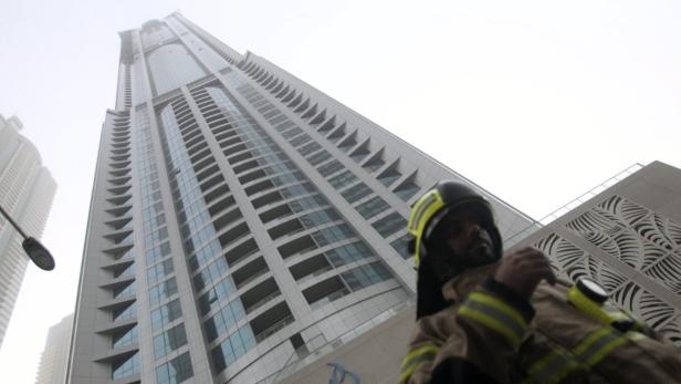 Ein Feuerwehrmann steht vor einem hohen Gebäude in Dubai.