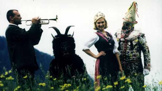 Eine Gruppe von Menschen in traditionellen Kostümen steht auf einer Wiese.