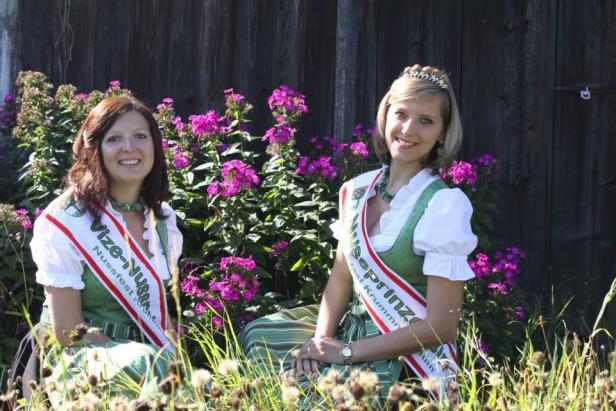 Die Nussfest-Vize-Nusskönigin und die Nussfest-Nussprinzessin posieren vor einem Holzzaun.