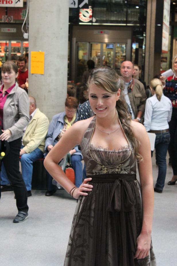 Eine junge Frau in einem Dirndl lächelt in die Kamera.