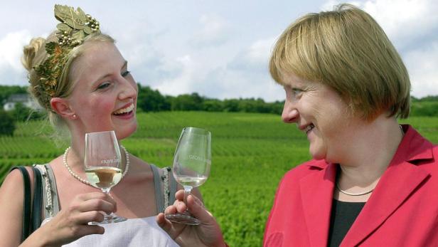 Angela Merkel mit einer Weinkönigin bei einer Weinprobe im Weinberg.