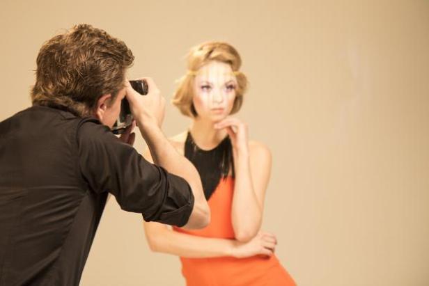 Ein Fotograf macht ein Foto von einem Model im Studio.