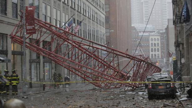 Ein umgestürzter roter Baukran liegt auf einer verschneiten Straße in New York City.