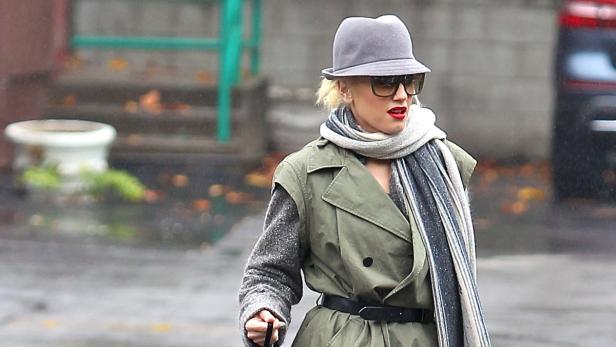 Gwen Stefani mit Hut, Schal und Trenchcoat auf der Straße.
