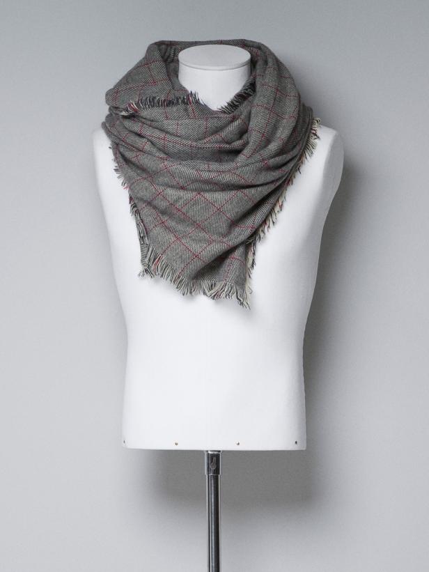 Ein grauer Schal mit rotem Karomuster ist um den Hals einer Schneiderpuppe drapiert.