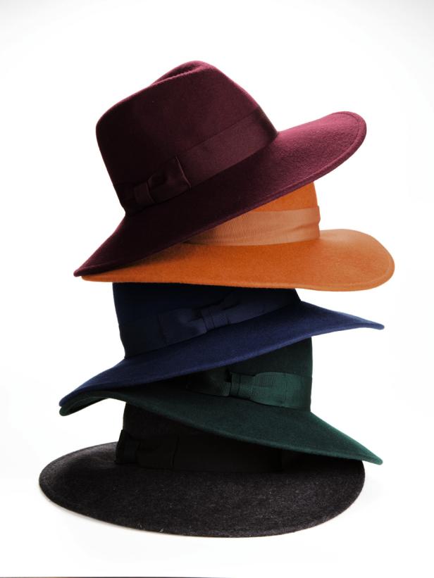 Ein Stapel aus fünf verschiedenfarbigen Damenhüten mit Schleifen auf einem weißen Hintergrund.