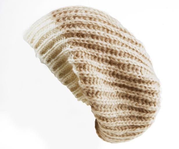 Eine gestrickte Baskenmütze in Beige- und Cremetönen.