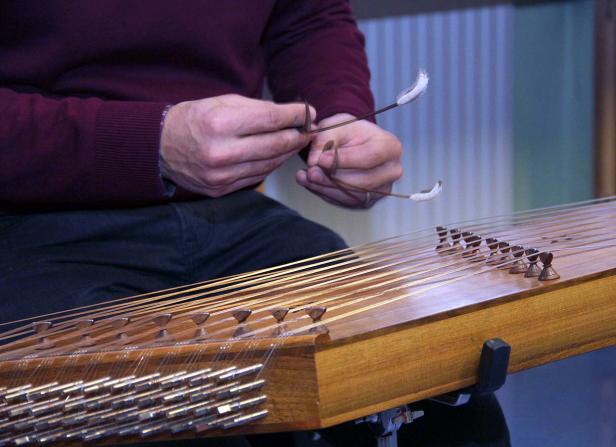 Ein Mann spielt mit zwei Schlägeln ein Hackbrett.