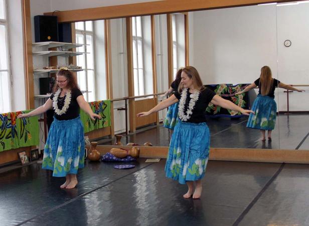 Zwei Frauen tanzen Hula in einem Tanzstudio mit Spiegelwand.