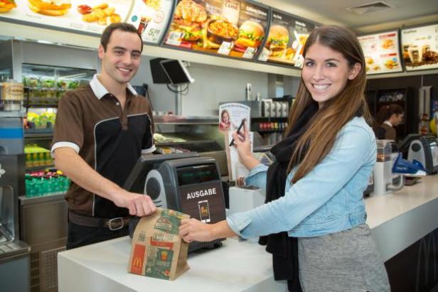 Eine Frau bezahlt ihre Bestellung mit dem Smartphone in einem McDonald’s Restaurant.