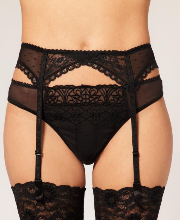 Eine Frau trägt schwarze, spitzenbesetzte Strapsstrümpfe und einen passenden Strapsgürtel.