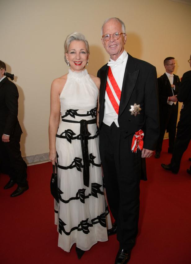 Ein Mann im Smoking mit einer Frau in einem weißen Kleid auf einem roten Teppich.