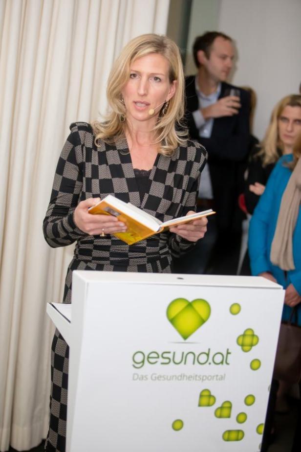 Eine Frau liest an einem Rednerpult mit dem Logo von gesund.at.